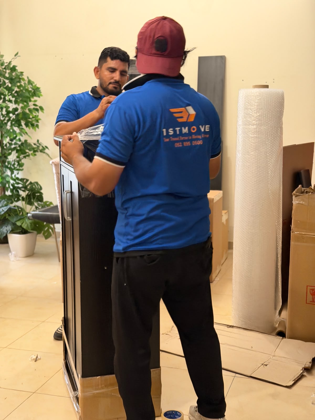 1stMove crew in branded uniforms wrapping a cabinet for transport in a Dubai home