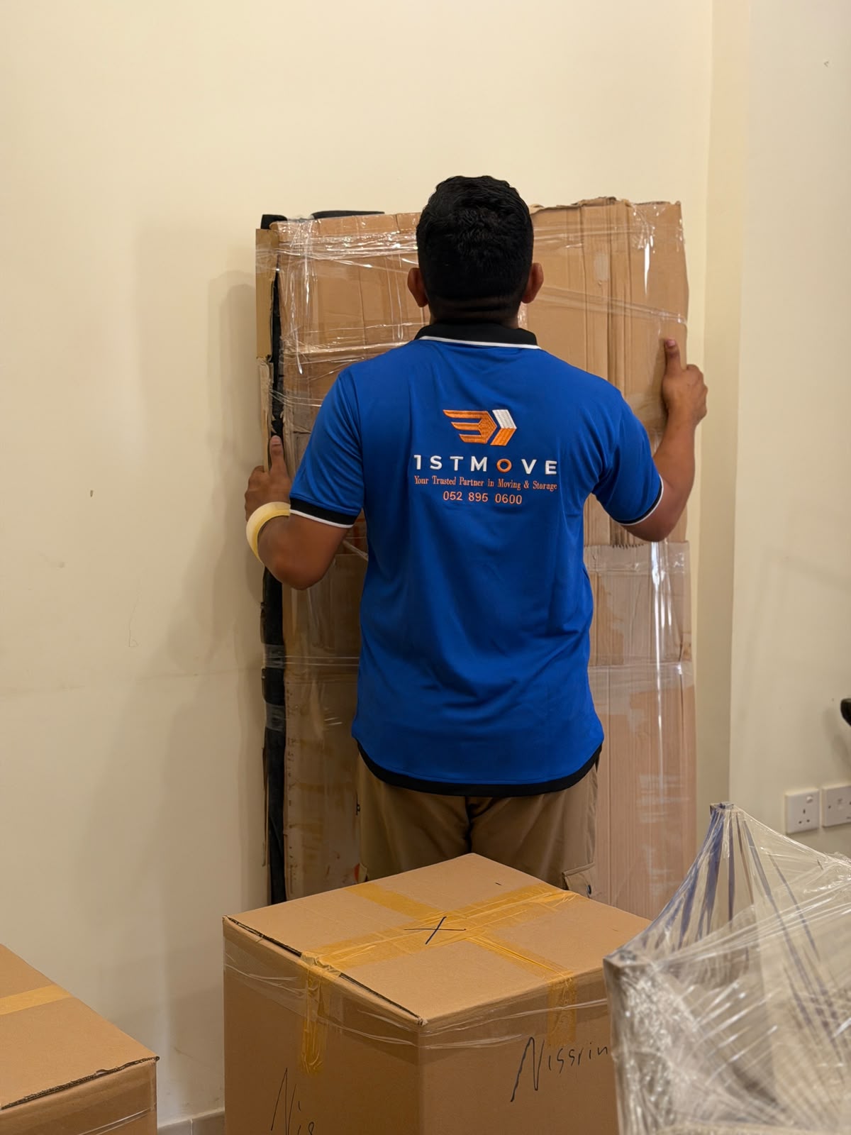 A 1stMove crew member in branded uniform carefully wrapping furniture during a real Dubai relocation