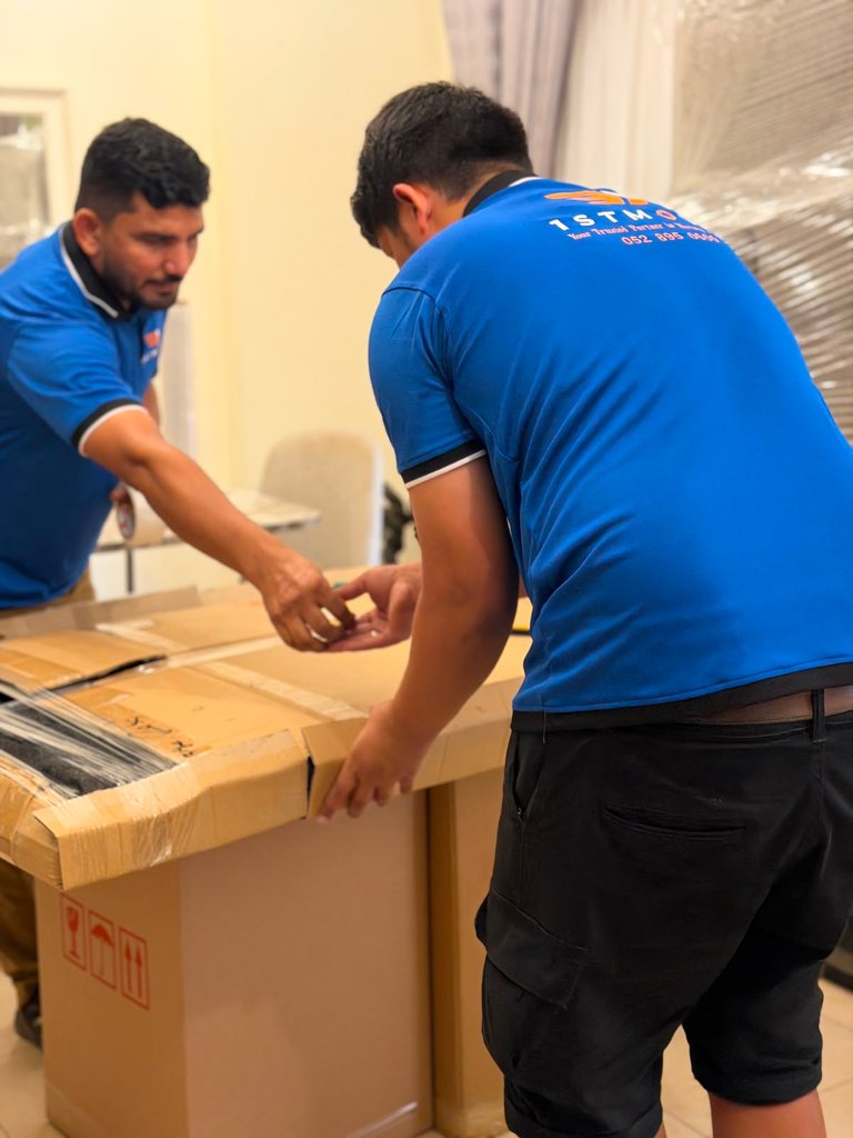 عضوان من طاقم 1stMove الحقيقي يقومان بتغليف صندوق نقل كبير معًا في الداخل